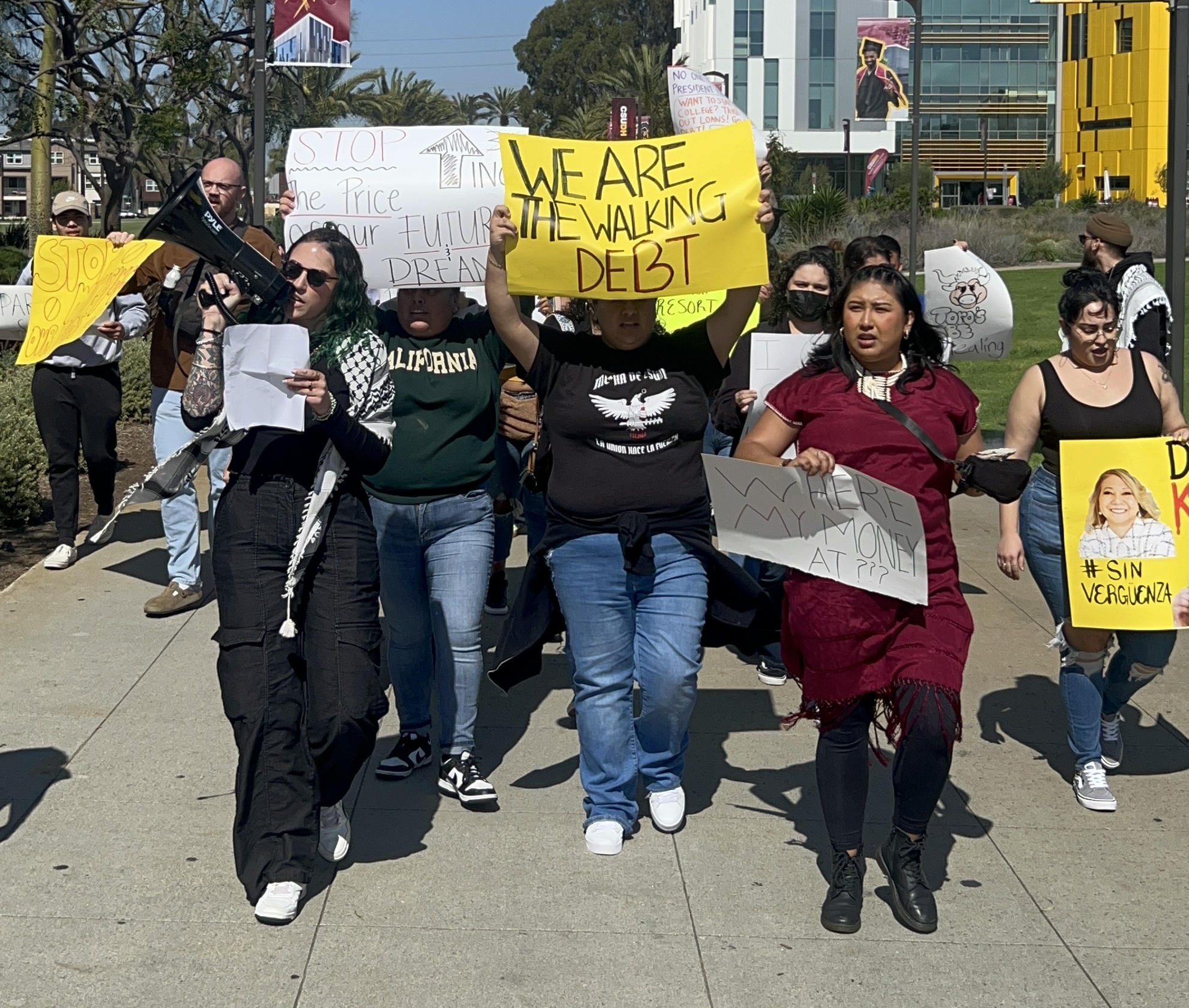 Photo of a protest with people holding yellow and white signs.