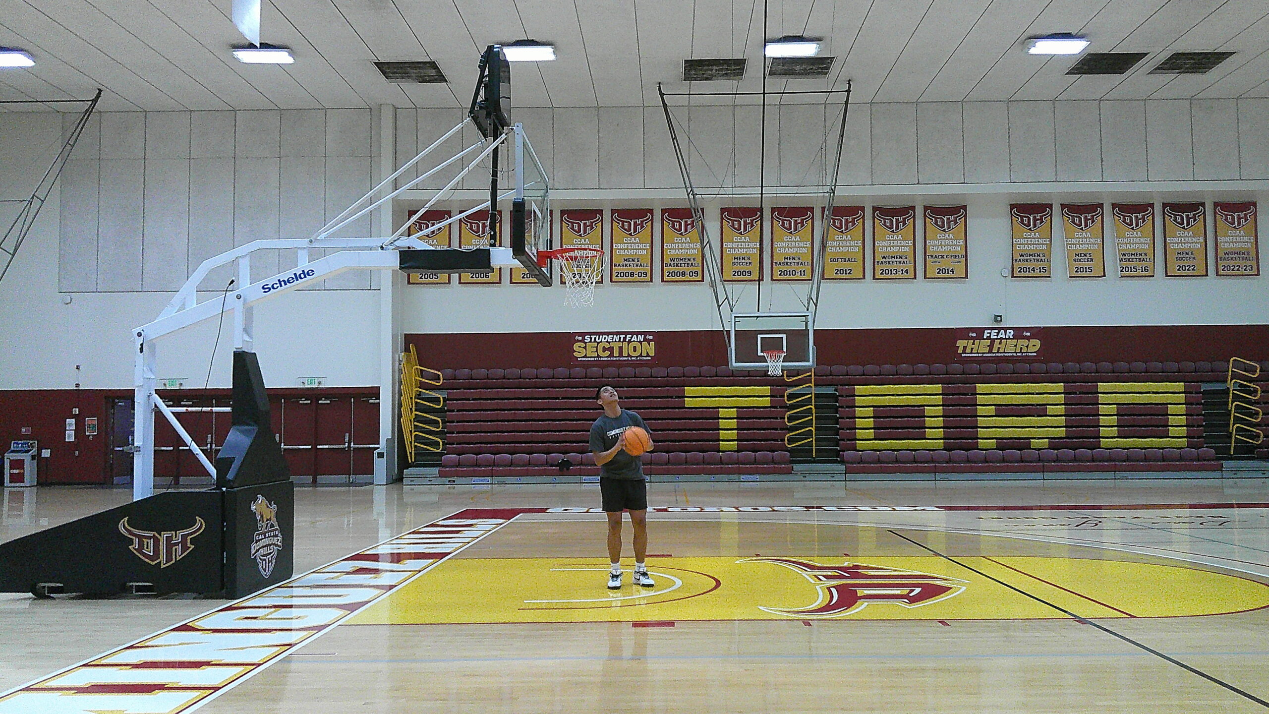 wide photo of a basketball court with a person in the middle